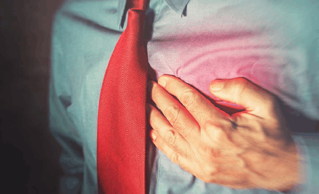 Muž v košili a kravatě se drží za srdce kvůli krevnímu tlaku