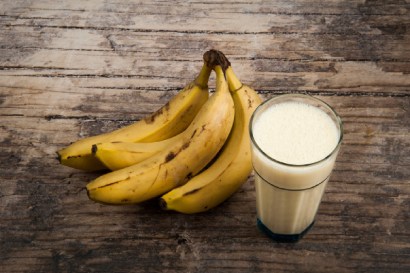 Banány na stole vedle sklenice s banánovým smoothie