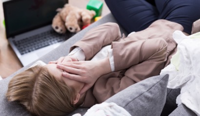 Vyčerpaná žena leží na gauči, ruce na tváři, únava z nedostatku železa