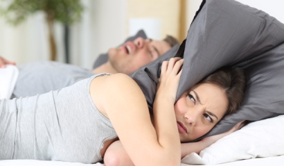 Partnerka chrápajícího muže si zakrývá hlavu polštářem