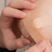 Ruka aplikuje náplast Omnifix Elastic na ránu k jejímu stažení