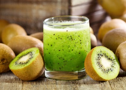 Zdravý nápoj z kiwi ve sklenici s dalšími kusy tohoto ovoce v zátiší