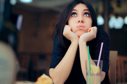 Žena sedí u stolu a pije drink, jelikož mírné pití alkoholu snižuje tlak více, než abstinence
