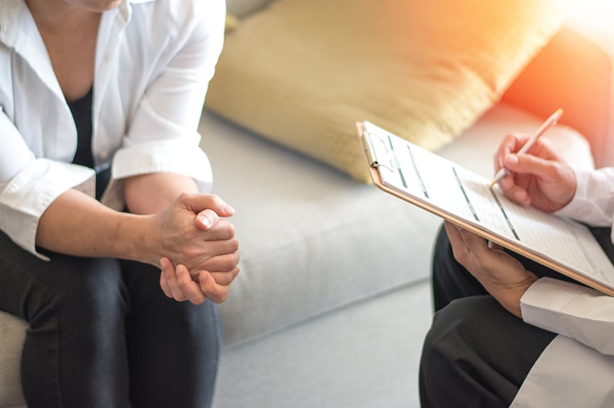Psychoterapeut konzultující ženu sedící s rukama v klíně