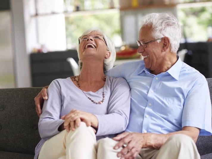 šťastný pár seniorů sedí na pohovce